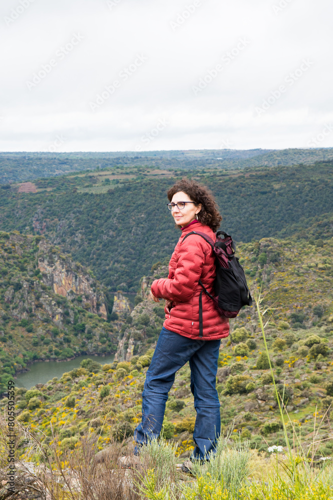 Woman hiking in the mountains. Standing with her backpack.