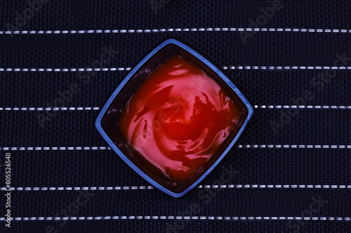 Glass bowl with ketchup, led on top. Close-up