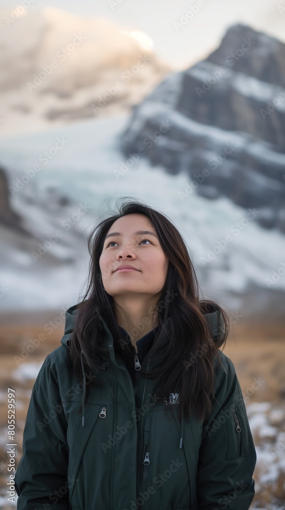 An Asian woman stands in front of towering snow-covered mountain An Asian woman stands in front of towering snow-covered mountain