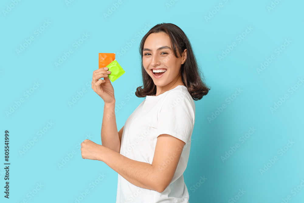 Young woman with condoms on blue background. Safe sex concept