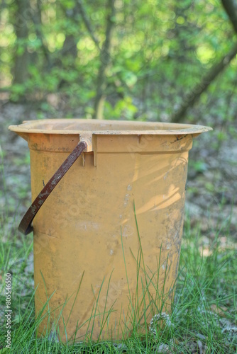 one large brown old plastic bucket dry closet stands in the green grass on the street