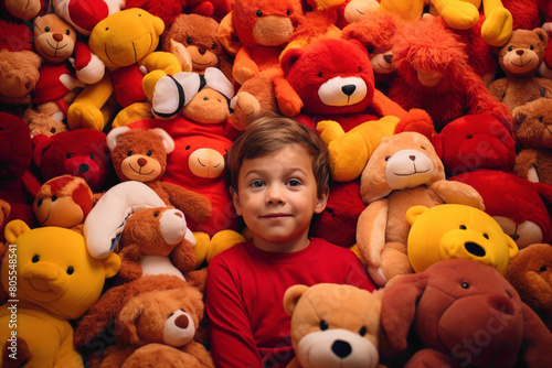 A toddler sitting amidst a pile of plush toys, a look of wonderment on their face, set agnst a bold red and yellow backdrop.