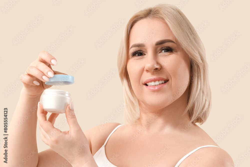 Beautiful mature happy woman with jar of cream on beige background Beautiful mature happy woman with jar of cream on beige background