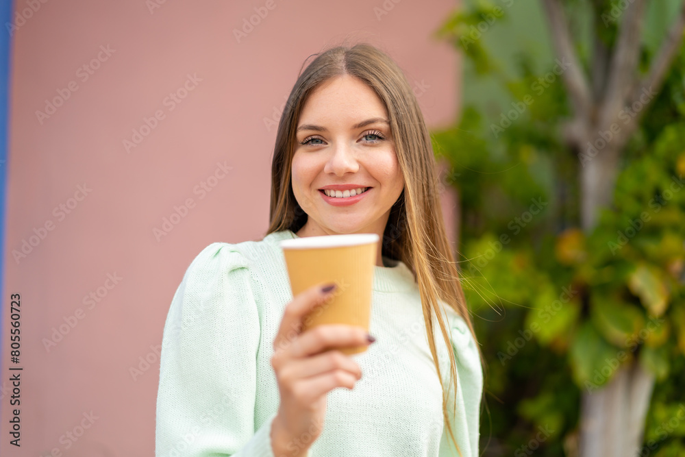 Young pretty blonde woman holding a take away coffee at outdoors with happy expression Young pretty blonde woman holding a take away coffee at outdoors with happy expression