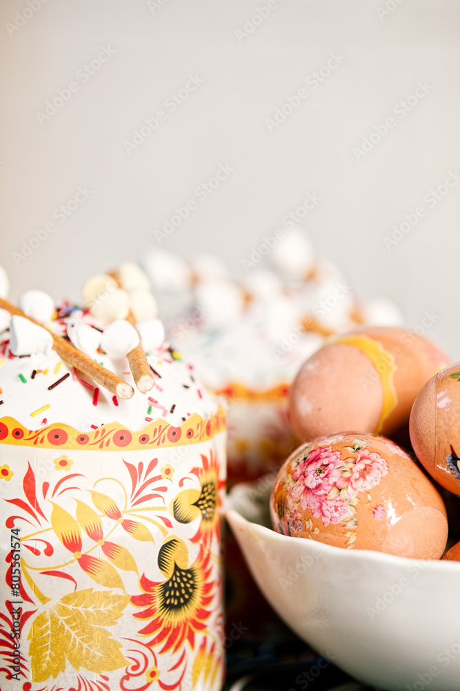 Composition of easter cake with protein glaze, sugar sprinkles, marshmallow on top and eggs decorated with patterns, on a with blurred background. Orthodox Easter in eastern Europe. Vertical photo Composition of easter cake with protein glaze, sugar sprinkles, marshmallow on top and eggs decorated with patterns, on a with blurred background. Orthodox Easter in eastern Europe. Vertical photo