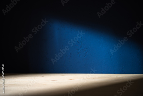 Table on dark blue wall background. Minimalist composition with abstract shadow on the wall and light reflections. Mock up for presentation, branding products, cosmetics food or jewelry.	