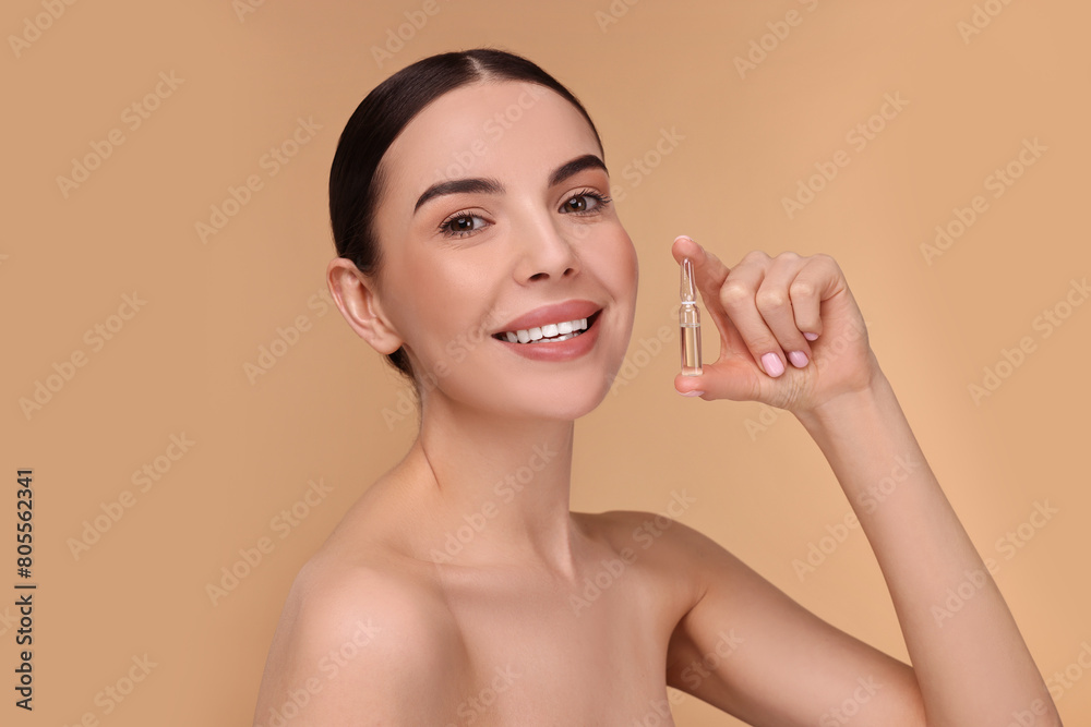 Beautiful young woman holding skincare ampoule on beige background Beautiful young woman holding skincare ampoule on beige background