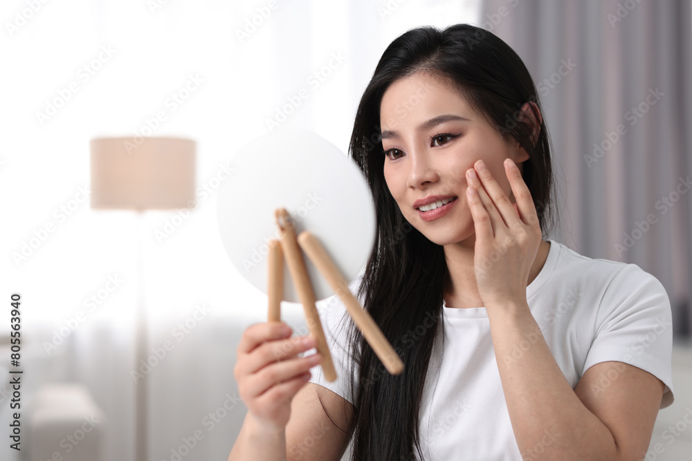 Woman with perfect skin looking at mirror indoors, space for text Woman with perfect skin looking at mirror indoors, space for text