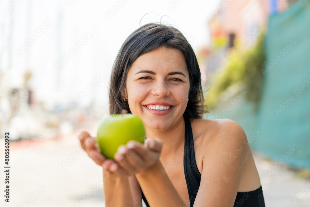 Young pretty Bulgarian woman at outdoors holding an apple Young pretty Bulgarian woman at outdoors holding an apple