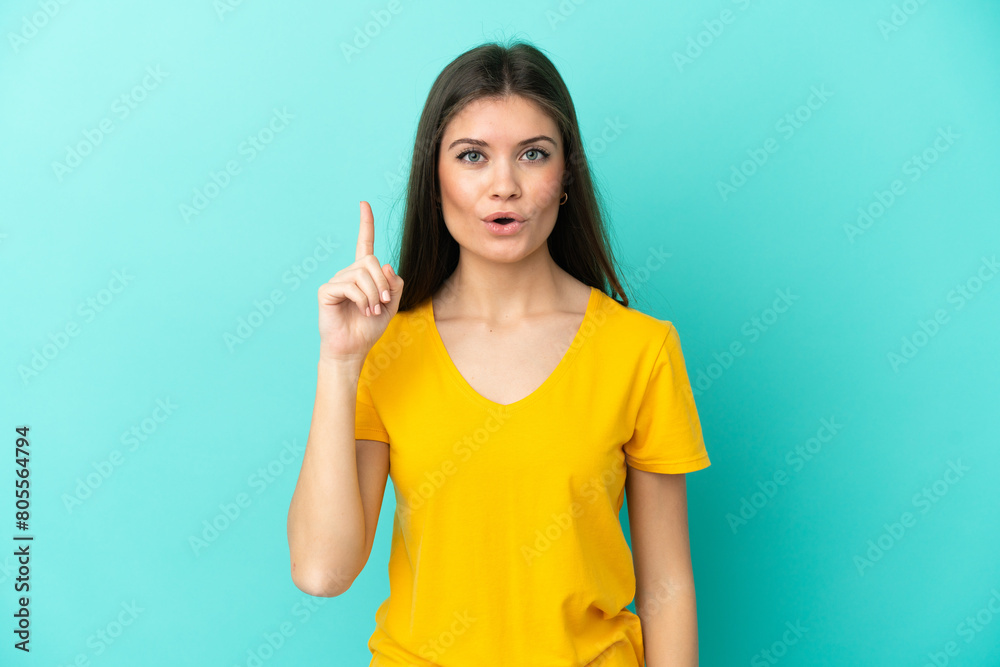Young caucasian woman isolated on blue background intending to realizes the solution while lifting a finger up Young caucasian woman isolated on blue background intending to realizes the solution while lifting a finger up