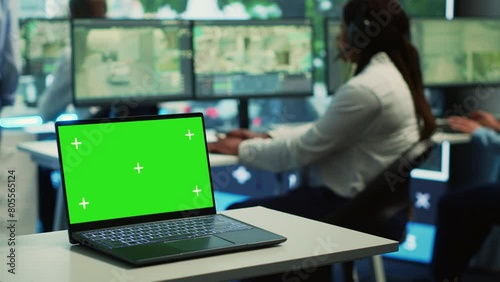 A laptop running isolated mockup display in a monitoring room, people working with surveillance footage from CCTV security cameras around the city. Greenscreen in a government agency. Camera A. photo