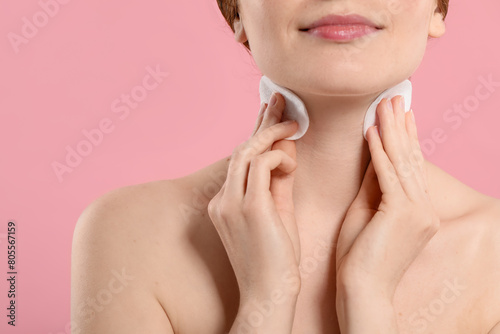Woman with freckles wiping neck on pink background  closeup
