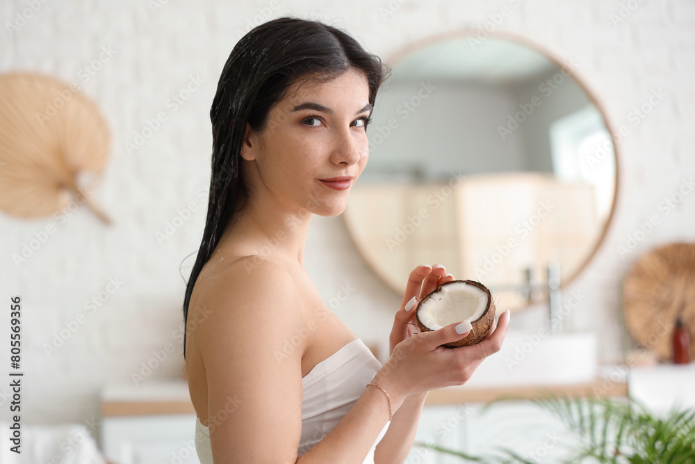 Beautiful young happy woman with hair mask and coconut in bathroom at home Beautiful young happy woman with hair mask and coconut in bathroom at home