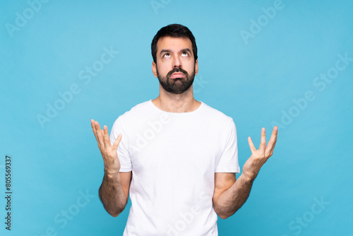 Young man with beard  over isolated blue background frustrated by a bad situation