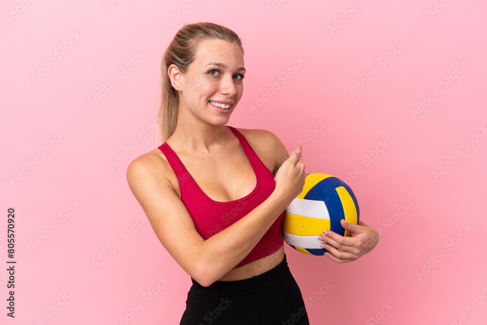 Young caucasian woman playing volleyball isolated on pink background pointing back Young caucasian woman playing volleyball isolated on pink background pointing back