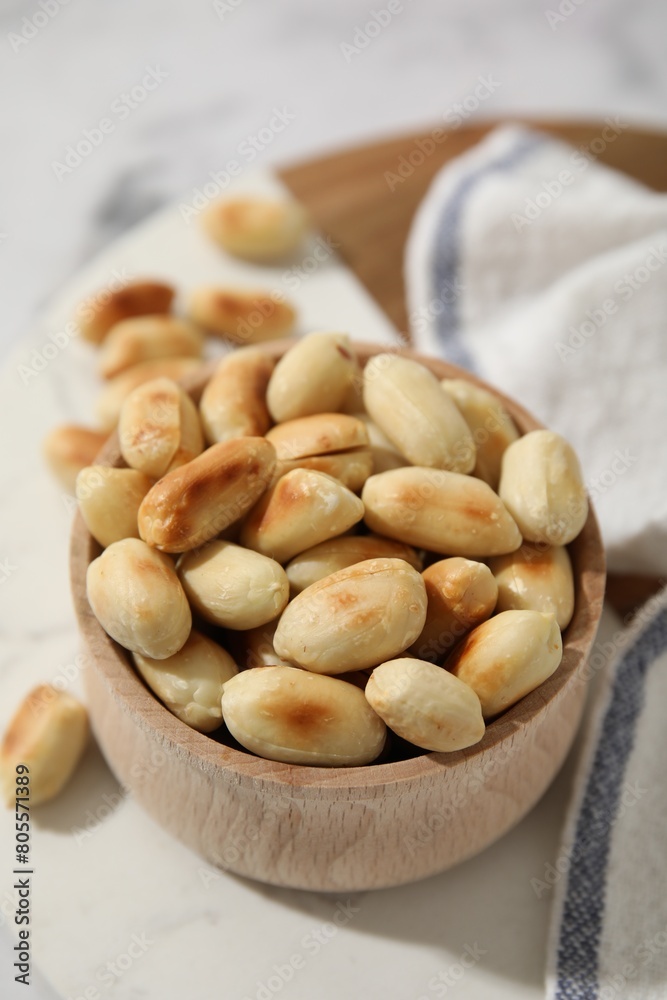 Roasted peanuts in bowl on white table, closeup Roasted peanuts in bowl on white table, closeup