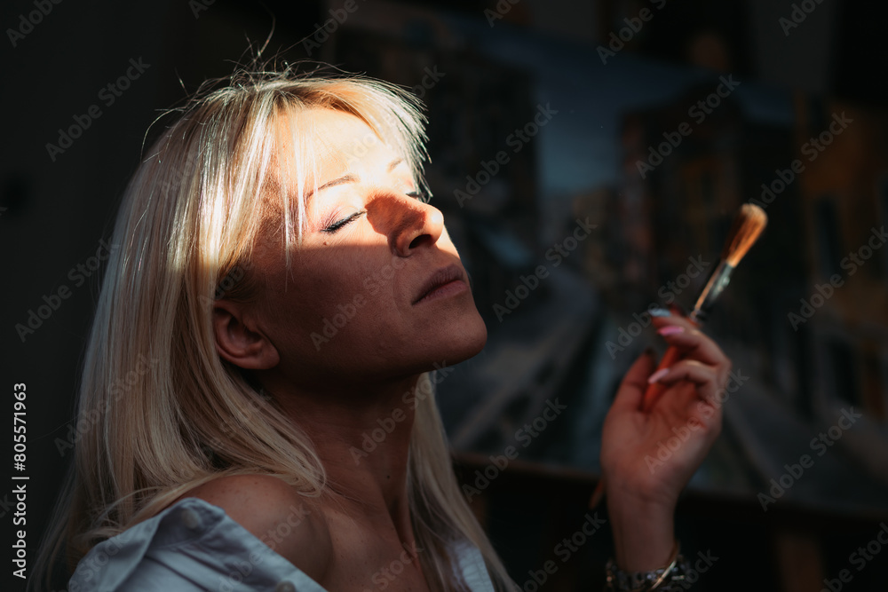 Obraz premium Young, female painter sitting by the window, under the sunlight