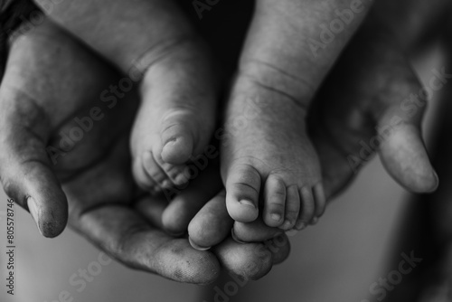 Father and son showing hands and feet of a new born