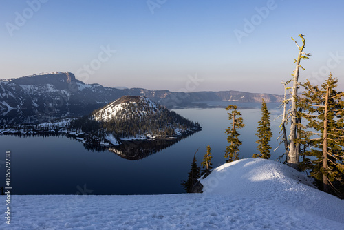 A snowy afternoon in Crater Lake National Park. The lake is calm and reflects wizard Island. photo