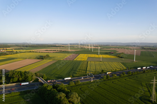 A road cutting through vibrant green grassland seen from above and wind turbines 5K drone view Hanover Wunstorf Kolenfeld Germany 