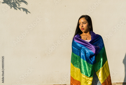 Hermosa joven hispanoamericana envuelta en una bandera del arco iris photo