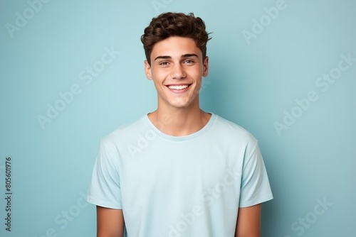 A young man is smiling and wearing a blue shirt