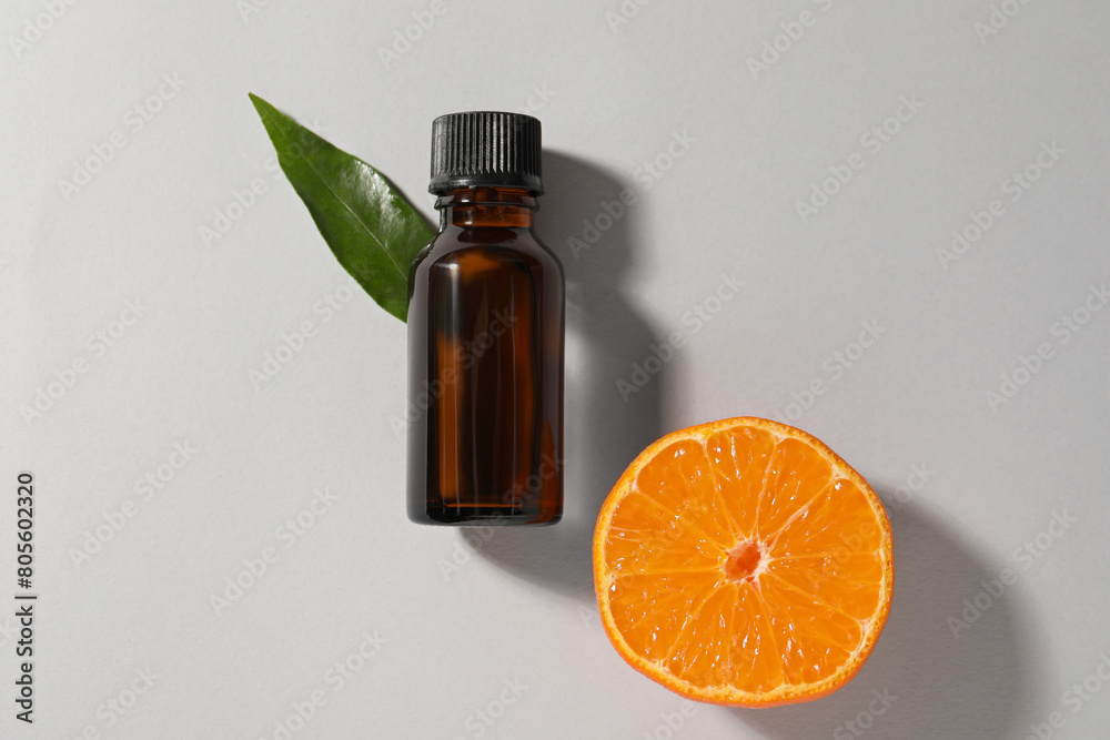 Aromatic tangerine essential oil in bottle, leaf and citrus fruit on grey table, top view Aromatic tangerine essential oil in bottle, leaf and citrus fruit on grey table, top view