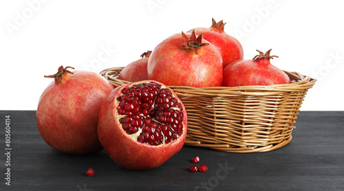 Konstfotografi Fresh pomegranates in wicker basket on black wooden table against white backgrou