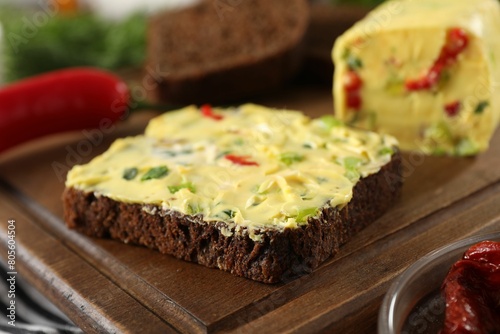 Tasty butter with green onion  chili pepper and rye bread on table  closeup