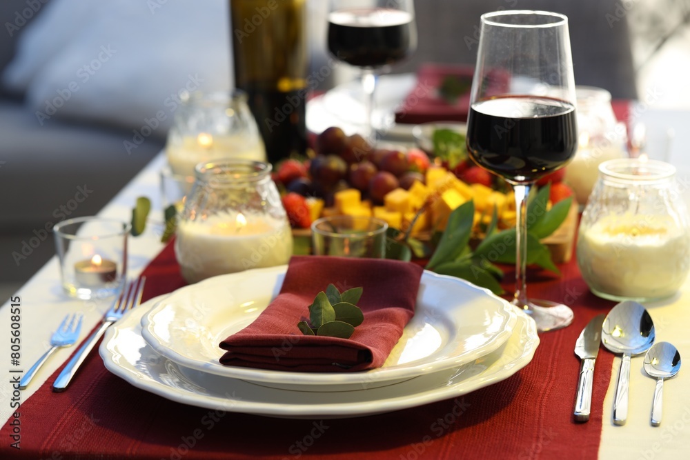 Stylish table setting with burning candles and wine indoors. Romantic dinner