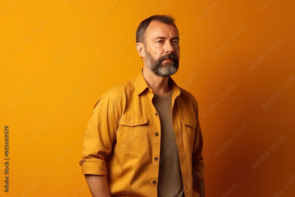 A man in a yellow shirt is standing in front of a yellow wall