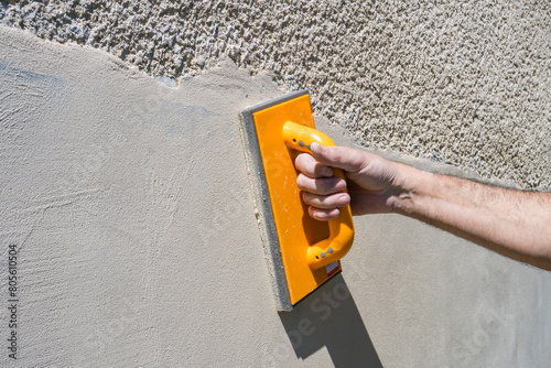 A worker putties a wall from the outside of a house. Construction concept photo