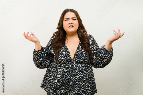 Canvas Print Confused gestures: plus-size woman expresses doubt against a white studio backdr