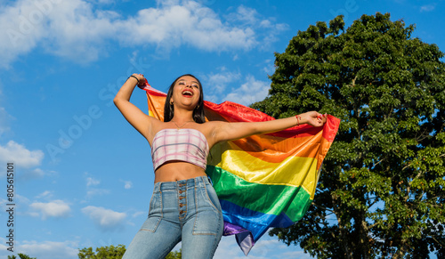 mujer joven hispanoamericana al aire libre en verano ondeando la bandera del orgullo gay  photo