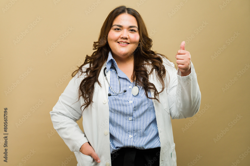 Beautiful plus-size female doctor posing with a thumbs-up gesture in a studio setting Beautiful plus-size female doctor posing with a thumbs-up gesture in a studio setting