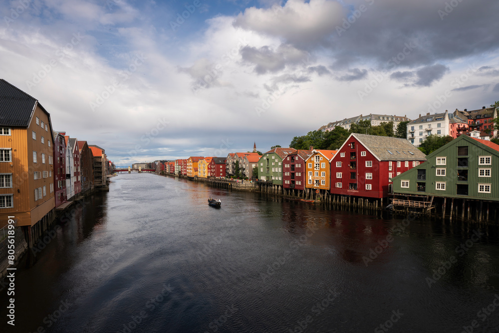colorful houses of Trondheim Norway with boat cruising down the river Nidelven