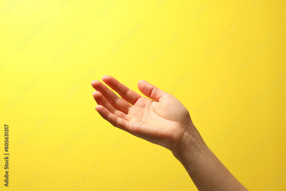 Woman holding something in hand on yellow background, closeup Woman holding something in hand on yellow background, closeup