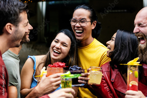 Young group of friends enjoying cocktail drink during happy hours at bar during summer vacation.