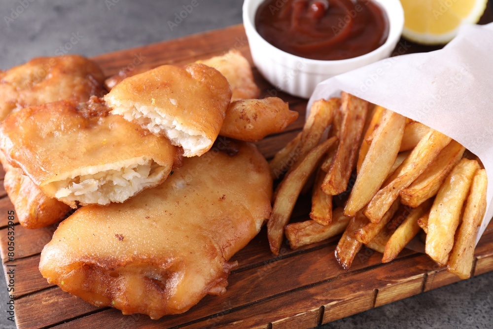 Tasty fish, chips and sauce on grey table, closeup Tasty fish, chips and sauce on grey table, closeup