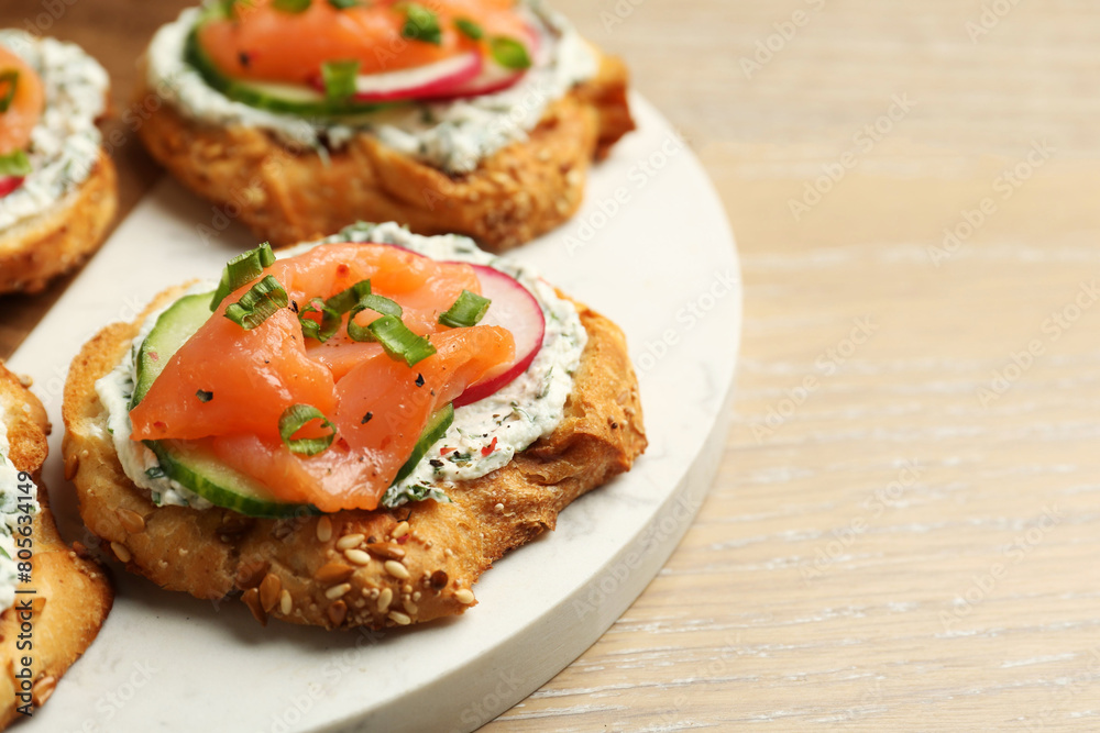 Tasty canapes with salmon, cucumber, radish and cream cheese on wooden table, closeup. Space for text Tasty canapes with salmon, cucumber, radish and cream cheese on wooden table, closeup. Space for text