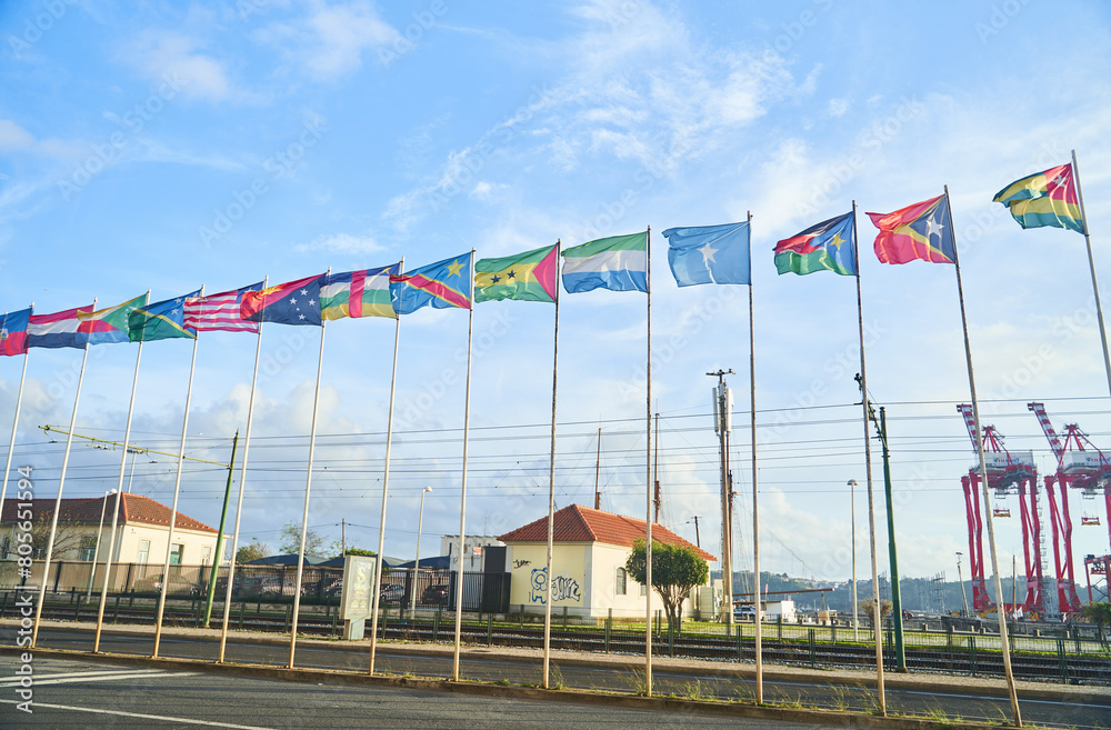 Flags hanged high in the air, fluttering against the cloudy sky, contrasting with the urban landscape of buildings and asphalt roads Flags hanged high in the air, fluttering against the cloudy sky, contrasting with the urban landscape of buildings and asphalt roads