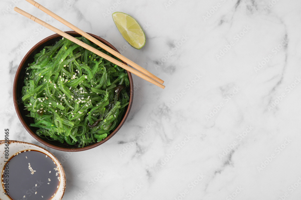 Tasty seaweed salad in bowl served on white marble table, flat lay. Space for text Tasty seaweed salad in bowl served on white marble table, flat lay. Space for text
