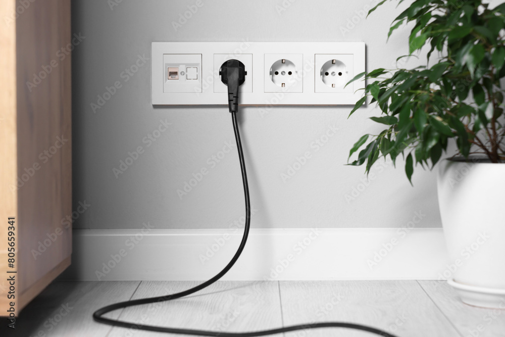 Power sockets and electric plug on grey wall