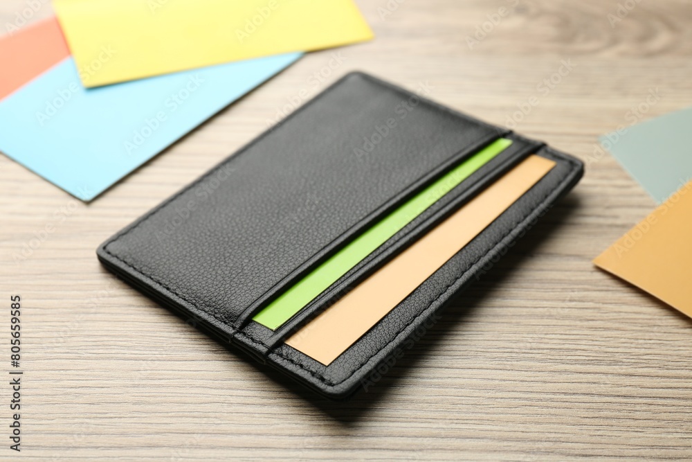 Fototapeta premium Leather business card holder with colorful cards on wooden table, closeup