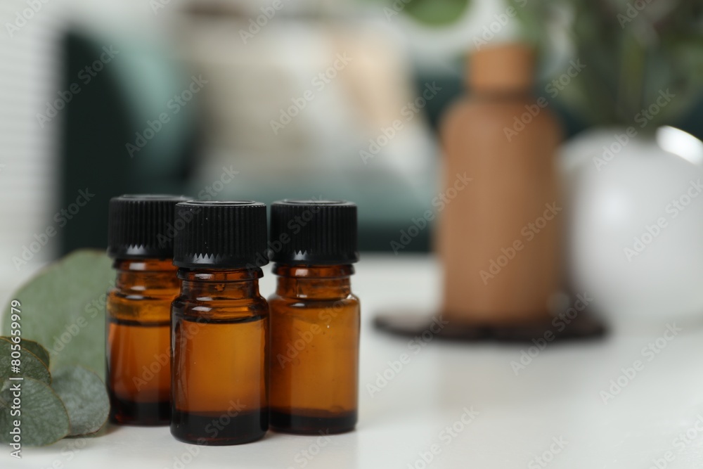 Aromatherapy. Bottles of essential oil and eucalyptus leaves on white table, space for text Aromatherapy. Bottles of essential oil and eucalyptus leaves on white table, space for text
