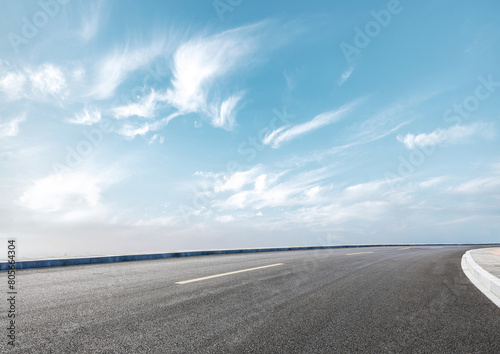 Modern highway cutting through the countryside under a clear blue sky