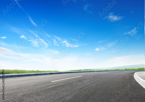 Modern highway cutting through Asian countryside under a clear blue sky