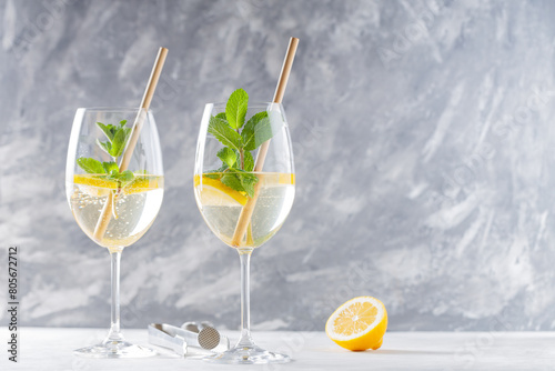 Trendy Elderflower Hugo Spritz Cocktail with Lemon Slice on Gray Concrete Background, Copy Space