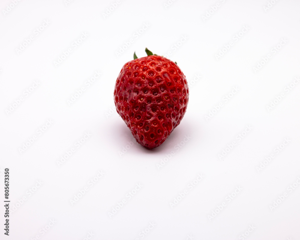 a very small strawberry on a white tablecloth with a leaf a very small strawberry on a white tablecloth with a leaf