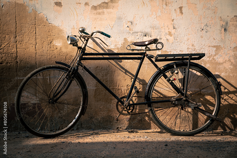 Vintage old bicycle leaning against dirty old wall background. Classic bike on decay wall with retro style.